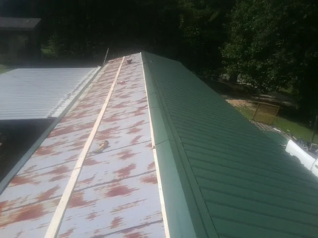 Old rusted panels beside newly installed green metal roofing — Wind Damage Roof Repair by Roofing Brothers in East Falmouth