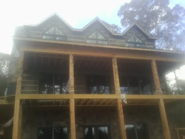 Dormers and porch framing on a large log home under construction — Roof Coating work by our crew in East Falmouth