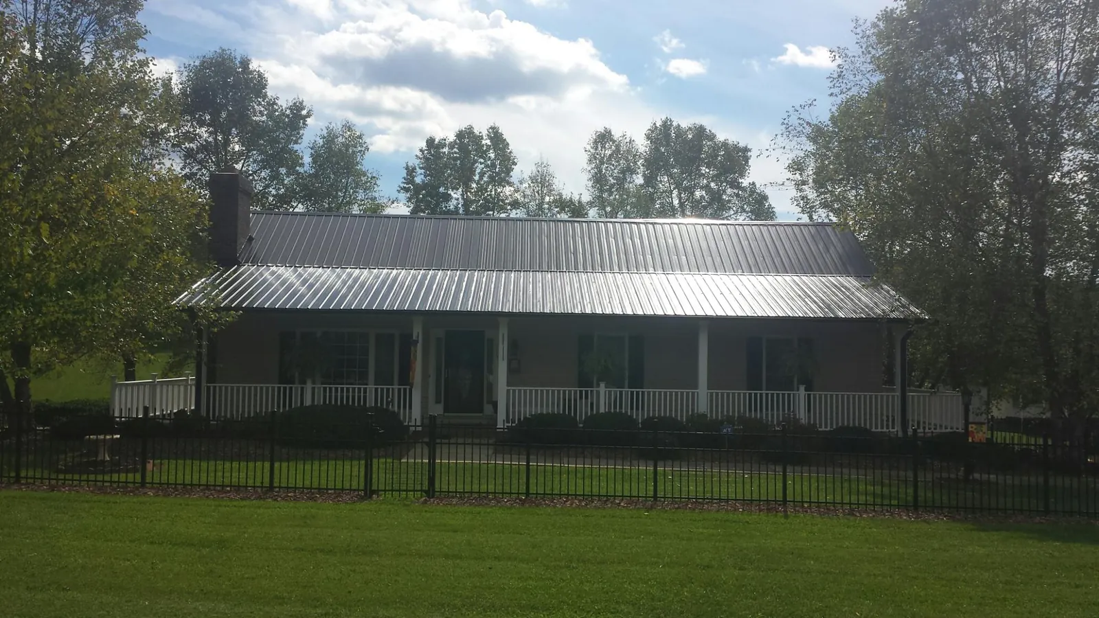 Gray metal roof on a brick ranch with a full width front porch — Gutter Guard Installation work by our crew in East Falmouth