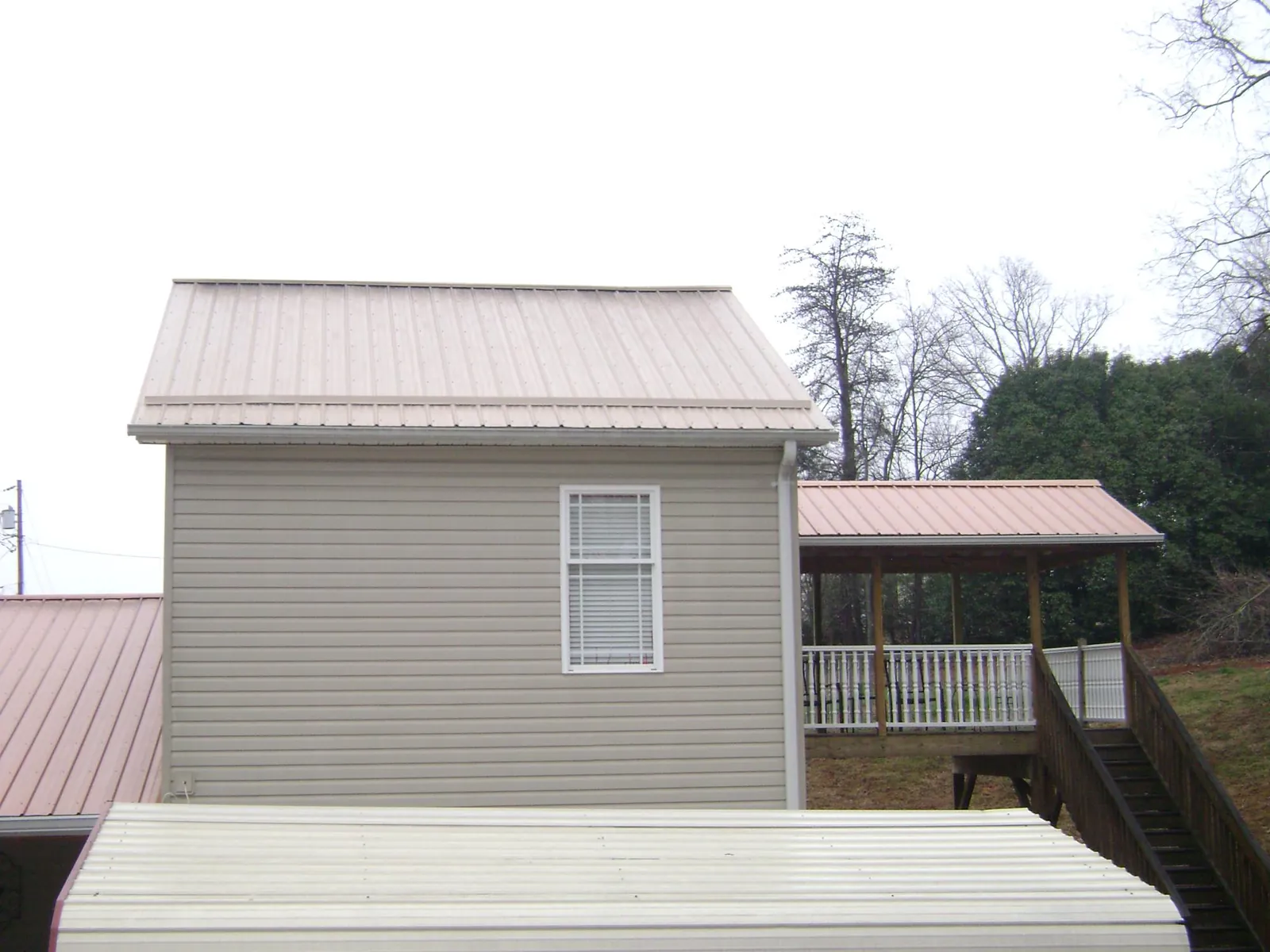 Tan metal roofs on a two story addition and attached porch, from a Roof Replacement job in East Falmouth