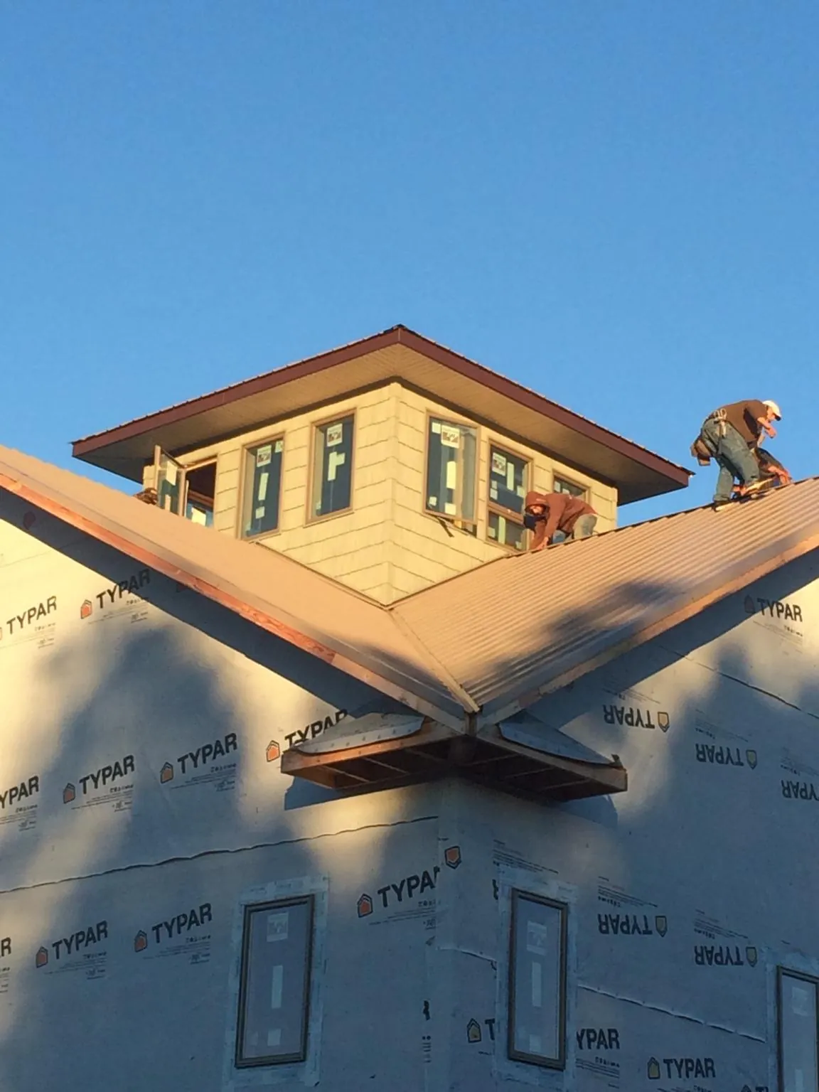 Roofers working around a rooftop cupola on a new metal roof at sunset — Roof Waterproofing in East Falmouth by Roofing Brothers